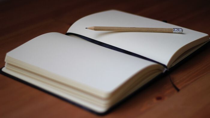 An open notebook with blank pages and a pencil. 