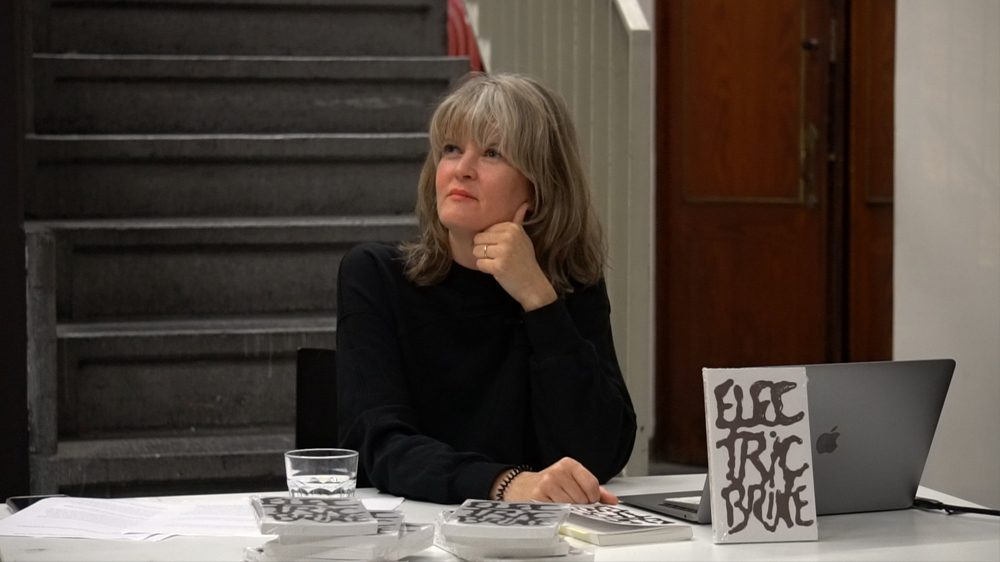 Jennifer Teets sitting by a table promoting her book.