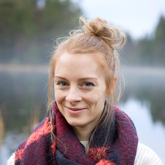 Closeup of a young smiling woman with a colourfoul scarf. A lake in the background.