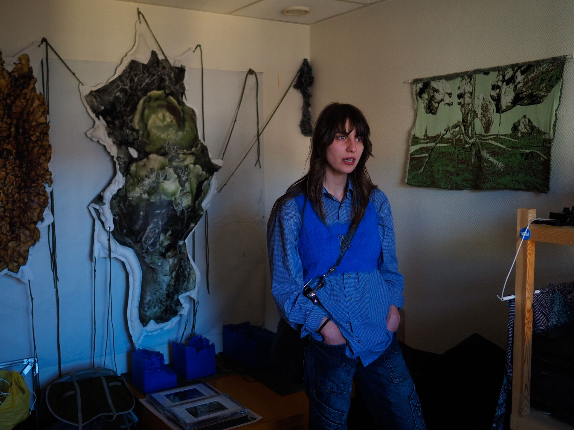 A woman in a blue shirt standing in front of an abstract artwork. 