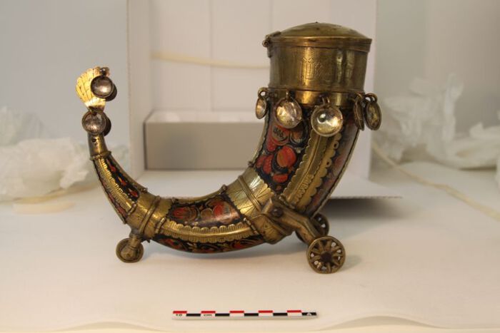 Image of a painted and gilded drinking horn with three wheels. 