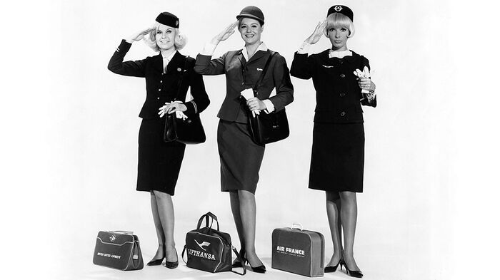 Black and white photo of three women in flight attendant uniforms. 