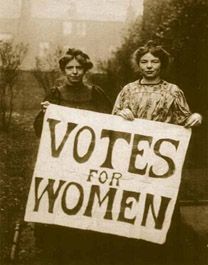 To women holding av poster where it says Votes for women. Photo.