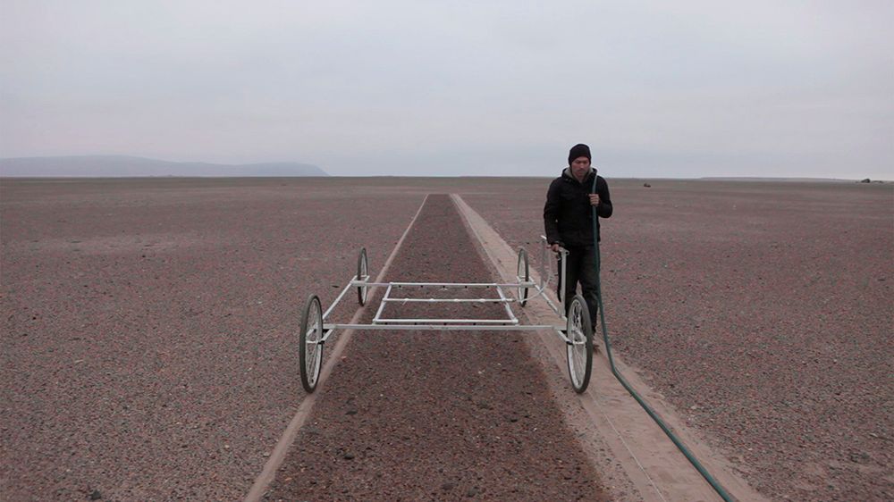 Landskap der sand møter himmel. En person som sykler en sykkel med fire hjul. Fotografi. 