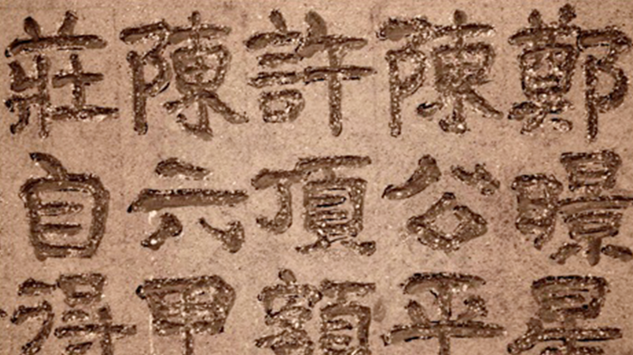 Image contains a brown clay plaquette with Chinese characters on it.