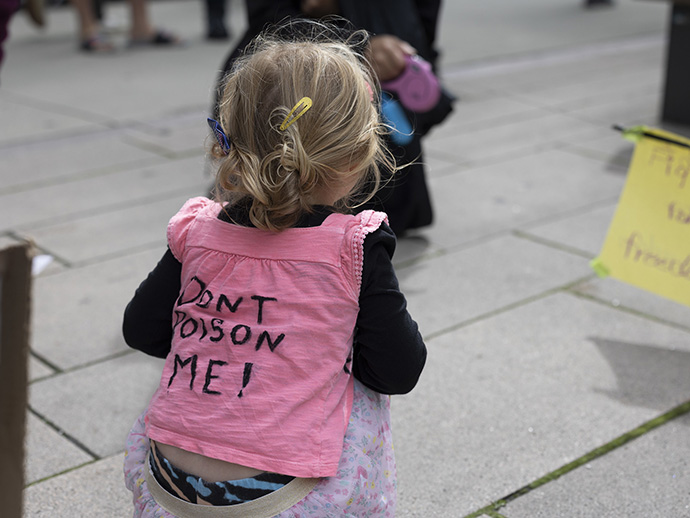 Liten jente sett bakfra, med rosa t-skjorte det står "don't poison me" på.