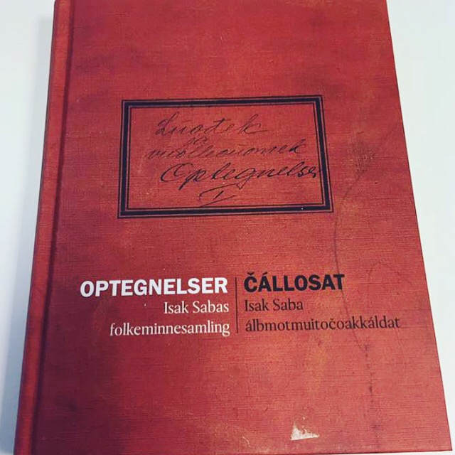 Bok med rød innbinding, på forsiden står det "Opptegnelser. Isak Saba. Folkeminnesamling" på norsk og samisk. Foto av boken.