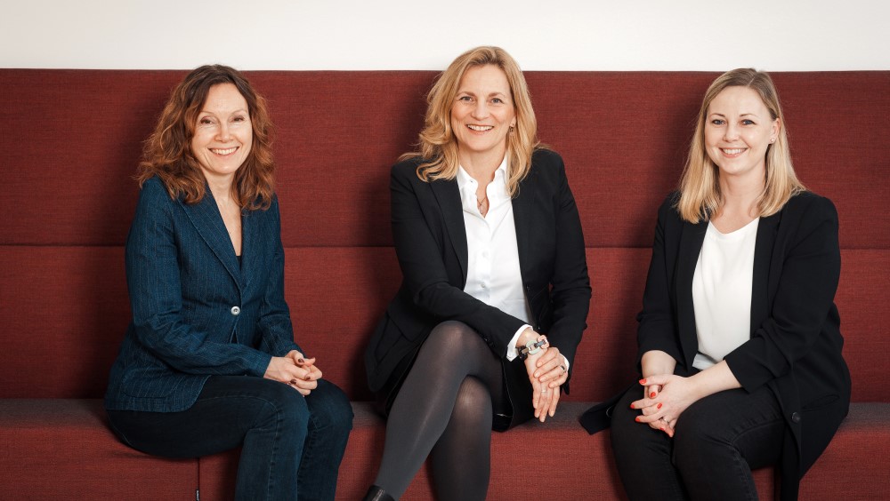 Ingebjørg Tonne, Unn Røyneland and Anne Charlotte Lindblom sitting on a red sofa, smiling