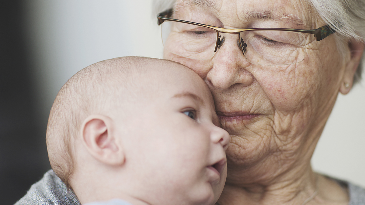 Eldre dame som holder en baby. Foto.