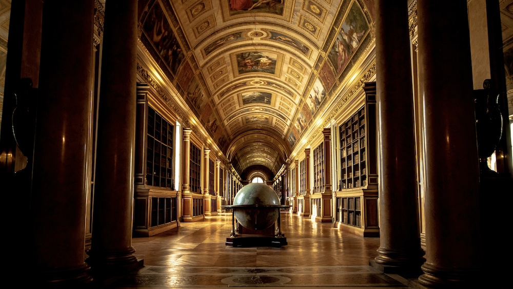 old library hall with bookshelves and a globe in the middle. 