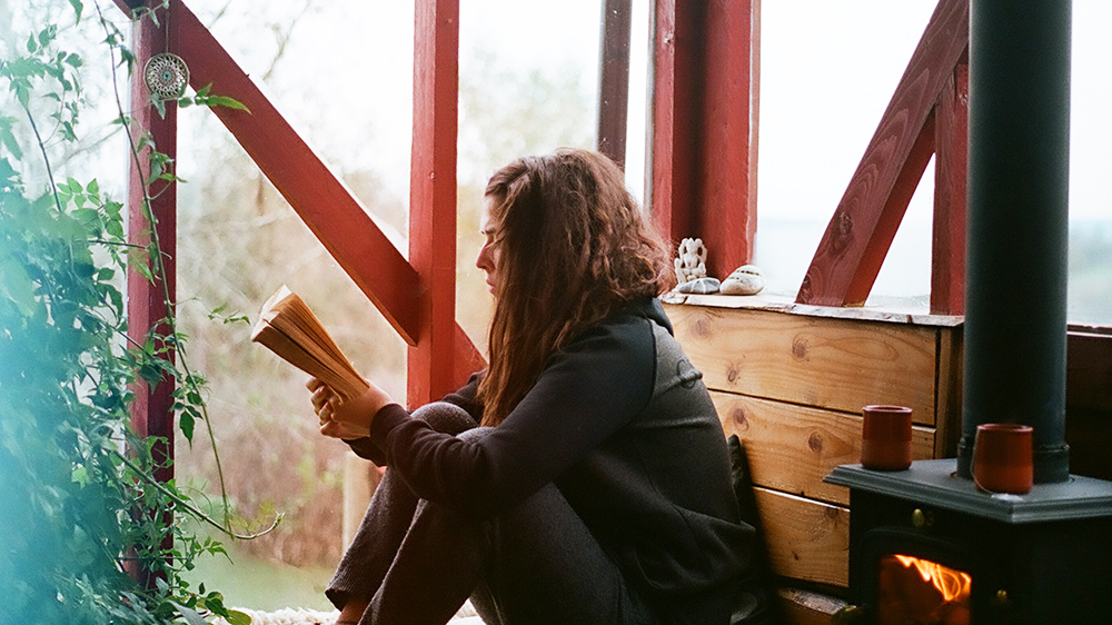 Ung kvinne leser bok på veranda