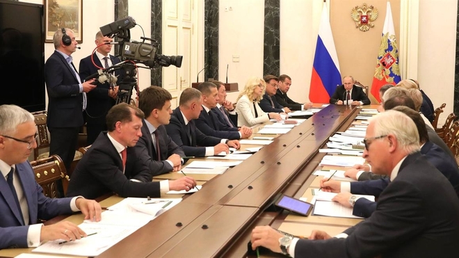 Russlands president Vladimir Putin sitter i enden av et stort konferansebord, i et møte med Russlands regjeringsmedlemmer.. Foto