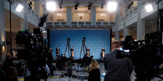 The norwegian government holds a press conference. Journalists and cameras are shown in front of them. Photo.  