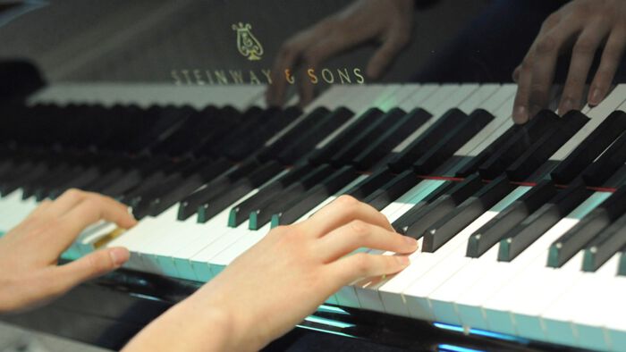 Bildet kan inneholde: musikk instrument, hånd, plan, tastatur, musiker.
