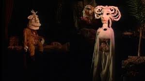 Stillbilde fra film, to dukker i et mørkt rom