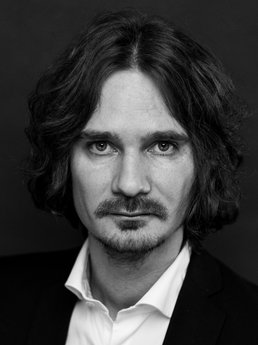 Mann med halvlangt hår og bart. Foto i svart-hvitt. 