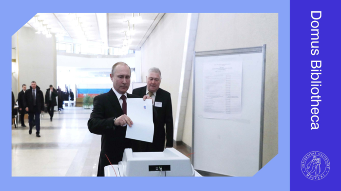 Mann i dress legger stemmeseddel i valgurne. Foto. 