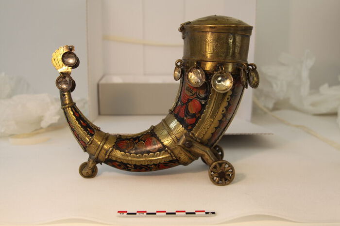 Bilde av et drikkehorn med rosemaling, mynter, tre hjul i gull, sølv og kobber