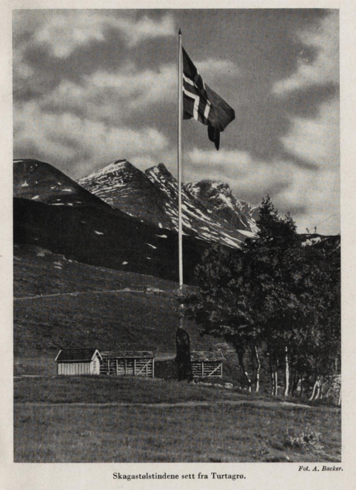 Et norsk flagg heist på stanga ved Turtagrø, men Skagastølstindene i bakgrunnen.